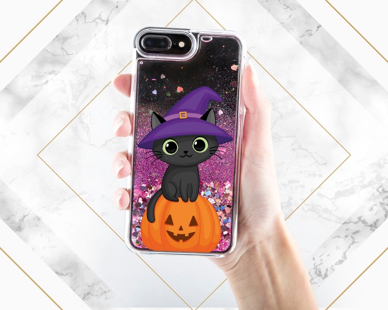 May include: A black cat wearing a purple witch hat sits on a carved orange pumpkin. The image is inside a clear phone case with pink and black glitter.