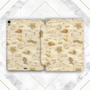 Op de afbeelding: Een tablet hoesje met een strandthema. De hoes heeft een zanderige achtergrond met schelpen, zeesterren, voetafdrukken en kleine flesjes. De kleuren zijn voornamelijk beige, bruin en geel, wat een kustesthetiek creëert.