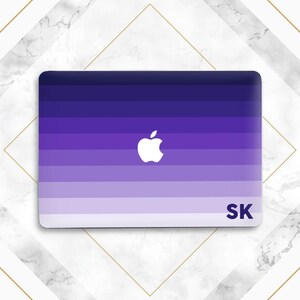 May include: A rectangular laptop skin featuring a horizontal gradient of purple shades, transitioning from dark violet at the top to light lavender at the bottom. A white Apple logo is centered, and the letters SK are printed in the bottom right corner.