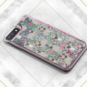 May include: A clear phone case with a pink glitter border and a design of pugs and flowers. The pugs are drawn in a cartoon style and are surrounded by pink, green, and purple flowers.