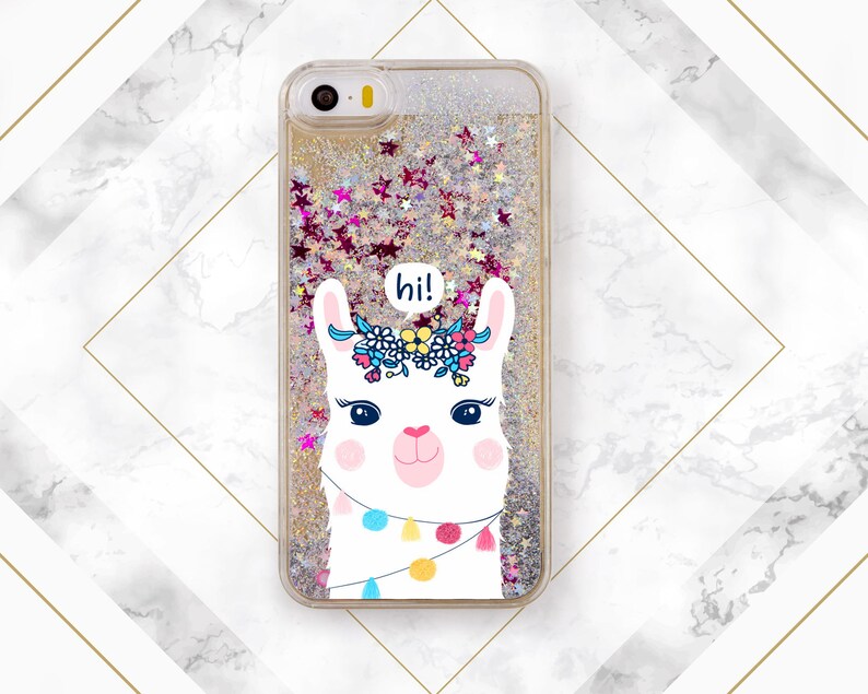 May include: A clear phone case with a gold glitter background and a white llama with a floral crown and the word "hi!" in a speech bubble. The llama is wearing a string of colorful tassels.