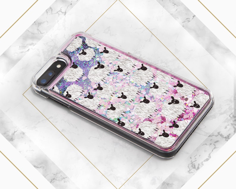 May include: A clear phone case with a silver glitter background and a repeating pattern of pink sheep. The case has a black border and a camera cutout.