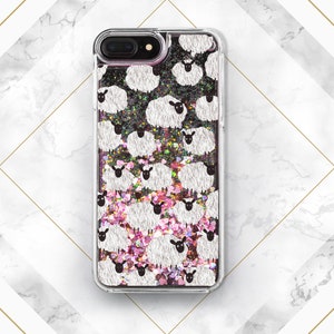 May include: A clear phone case with a glittery pink and black background. The case features a repeating pattern of white sheep with black faces.