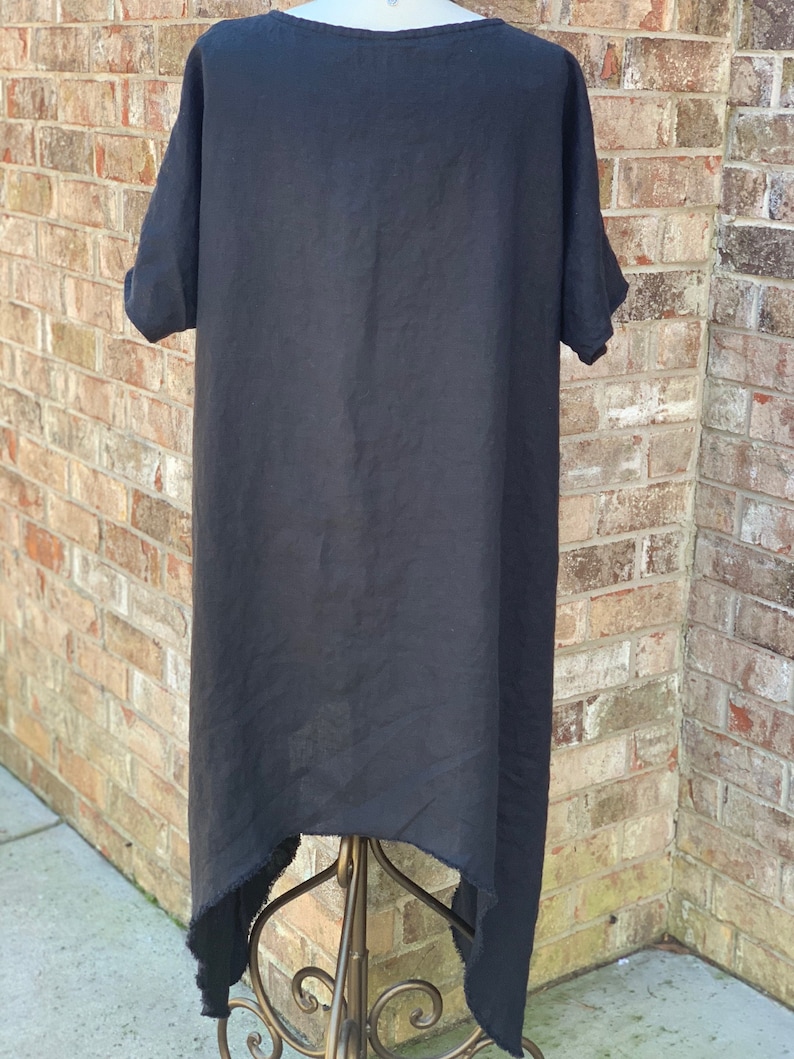 May include: Black linen dress with a high low hemline and short sleeves. The dress is hanging on a gold stand.