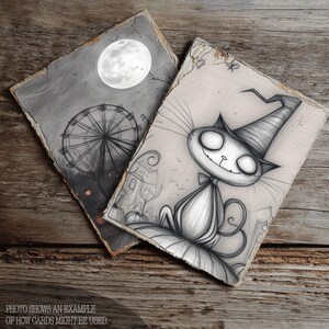 May include: Two Halloween-themed art prints. One features a Ferris wheel under a full moon, the other a smiling cat wearing a witch hat. The prints are in black and white with a distressed, vintage look. The text at the bottom reads: PHOTO SHOWS AN EXAMPLE OF HOW CARDS MIGHT BE USED.