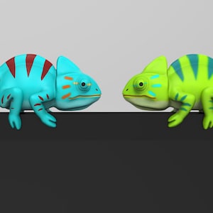 May include: Two toy chameleons facing each other. The chameleon on the left is blue with red stripes and orange accents. The chameleon on the right is green with blue stripes.
