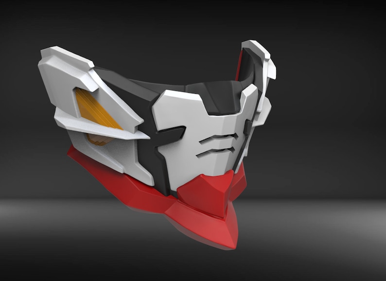 May include: A white, black and red plastic mask with a geometric design. The mask has a sharp, angular shape and features a small, rectangular opening for the eyes.