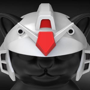 May include: A black cat figurine wearing a white and red robotic helmet. The helmet has a central red crest and angular details, with black ears peeking out. The cat's face is visible, with closed eyes and a slight smile.