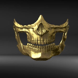 May include: A gold-colored skull mask with a detailed design. The mask is made of metal and has a realistic skull shape.