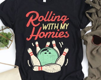 May include: Black t-shirt featuring a vintage-style graphic of bowling pins and a bowling ball. The text "Rolling with my Homies" is printed in red and white.