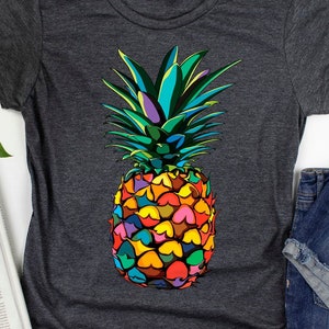 May include: A dark gray t-shirt with a colorful pineapple graphic. The pineapple is made up of different colored shapes and has a green top.