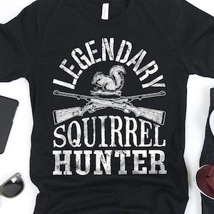 May include: Black t-shirt with a white graphic design that says "Legendary Squirrel Hunter" with a cartoon squirrel and two crossed rifles.