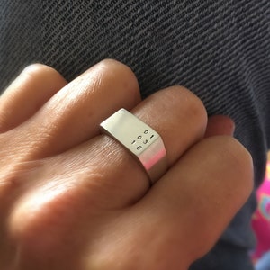 Könnte beinhalten: Ein silberner Ring mit einem rechteckigen Band, das mit den Zahlen "1008" graviert ist.