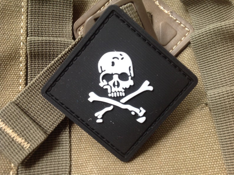 May include: A black diamond-shaped patch with a white skull and crossbones design.