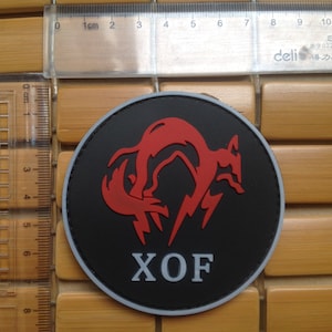 May include: A black and red embroidered patch with a stylized fox and the text "XOF".