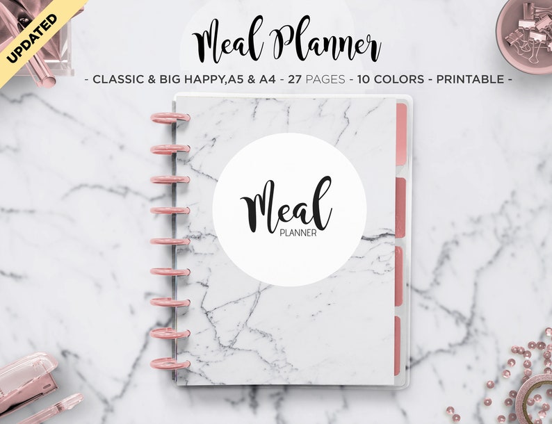 May include: A white marble-patterned meal planner with a pink ring binder and dividers. The planner has a white circle with the text "Meal Planner" in black cursive.