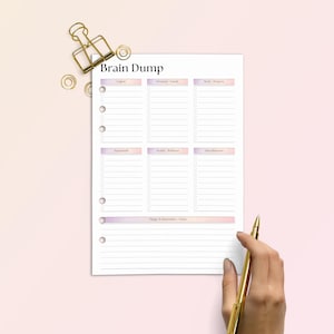 Op de afbeelding: Een plannerpagina met de titel "Brain Dump" en secties voor lijsten. De pagina is wit met een roze en paarse gradi&euml;nt aan de boven- en onderkant. Een gouden pen en paperclip liggen naast de pagina op een roze achtergrond.