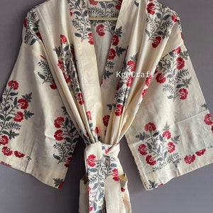 Pu&ograve; includere: Una vestaglia in cotone color crema con una stampa floreale in tonalit&agrave; di rosso e grigio. La vestaglia ha una cintura da legare e maniche lunghe.