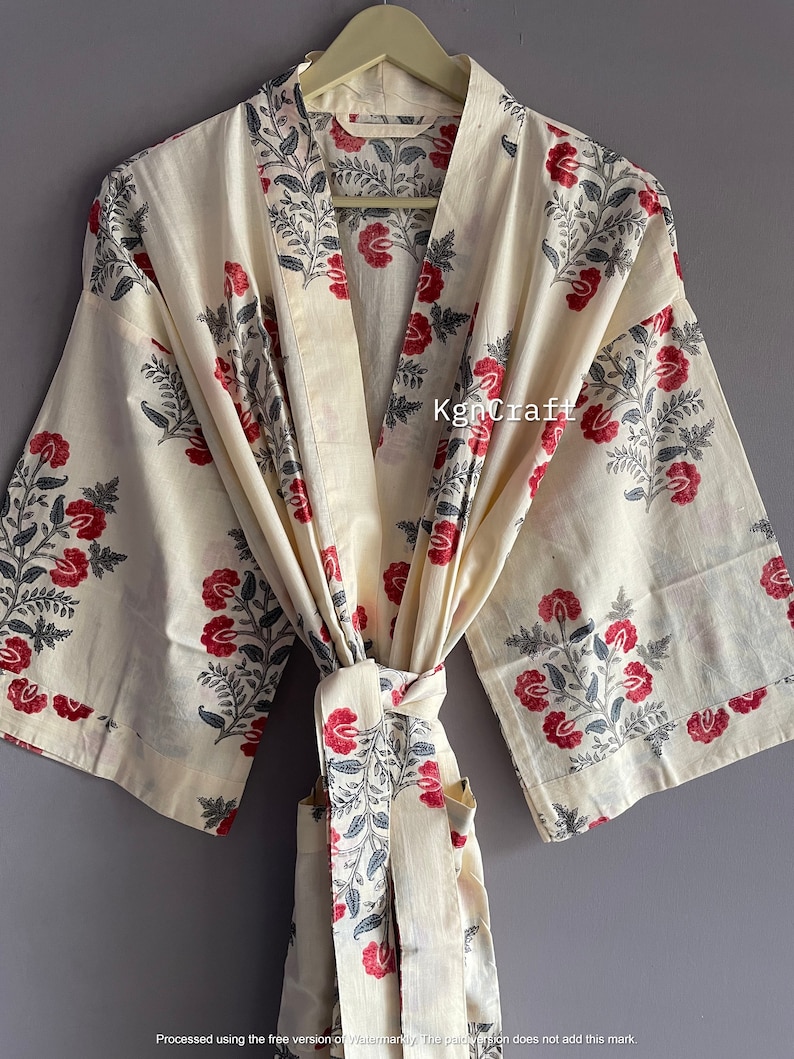 Pu&ograve; includere: Una vestaglia in cotone color crema con una stampa floreale in tonalit&agrave; di rosso e grigio. La vestaglia ha una cintura da legare e maniche lunghe.
