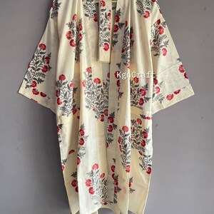Pu&ograve; includere: Un kimono in cotone color crema con una stampa floreale in tonalit&agrave; di rosso e grigio. Il kimono ha una chiusura a nodo e maniche lunghe.