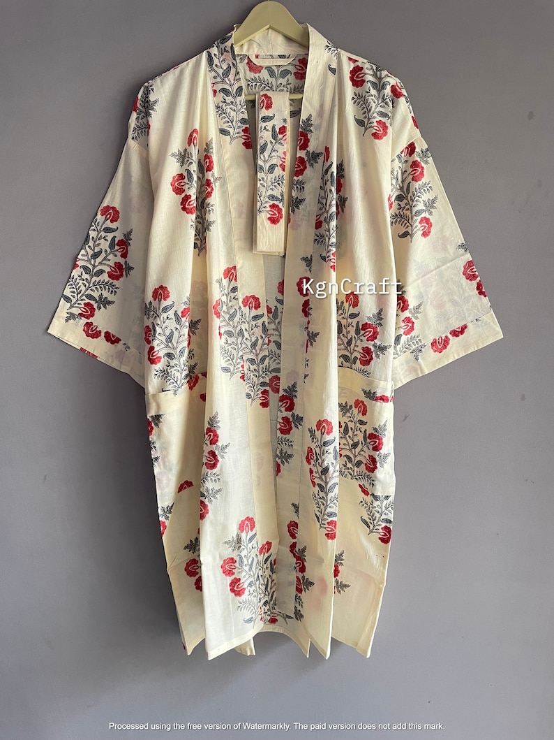 Pu&ograve; includere: Un kimono in cotone color crema con una stampa floreale in tonalit&agrave; di rosso e grigio. Il kimono ha una chiusura a nodo e maniche lunghe.