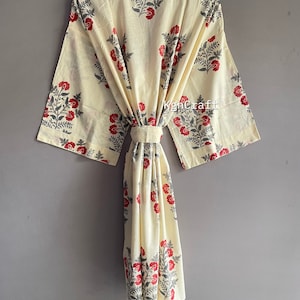 Pu&ograve; includere: Una vestaglia in cotone color crema con stampa floreale in tonalit&agrave; di rosso e grigio. La vestaglia ha una cintura da legare e maniche lunghe.