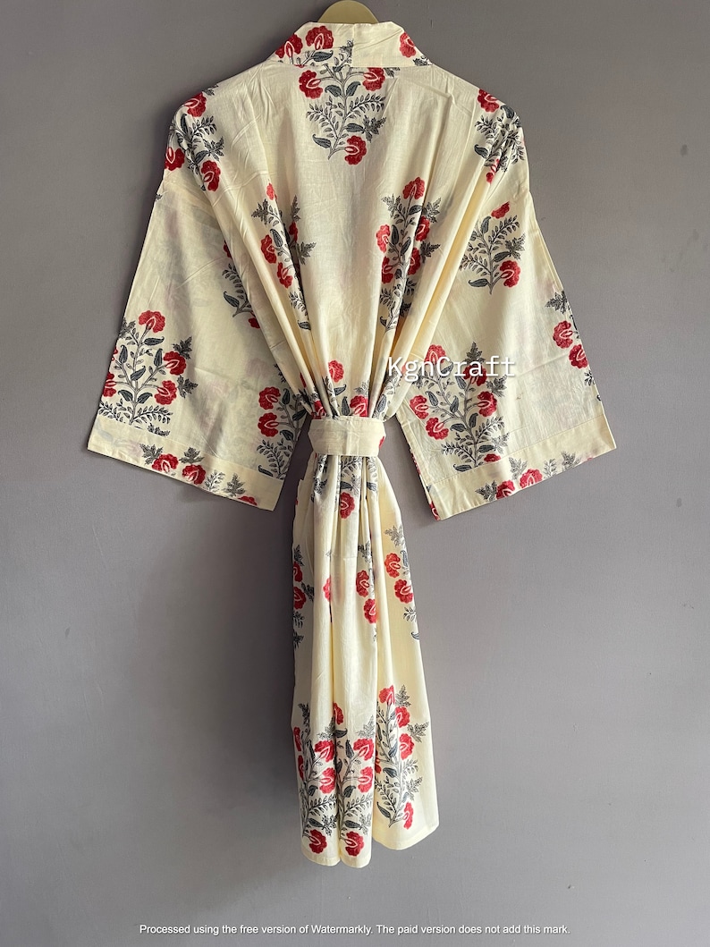 Pu&ograve; includere: Una vestaglia in cotone color crema con stampa floreale in tonalit&agrave; di rosso e grigio. La vestaglia ha una cintura da legare e maniche lunghe.