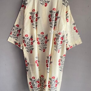 Pu&ograve; includere: Un kimono in cotone color crema con una stampa floreale in tonalit&agrave; di rosso e grigio. Il kimono ha un colletto e maniche a tre quarti.