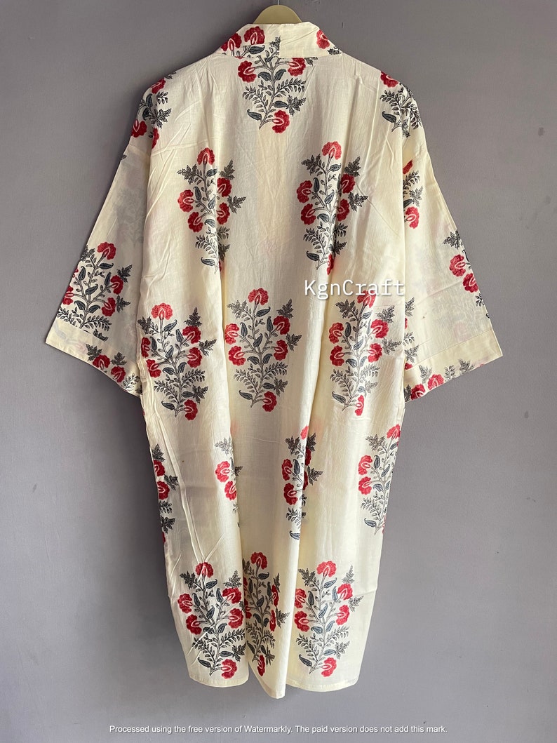 Pu&ograve; includere: Un kimono in cotone color crema con una stampa floreale in tonalit&agrave; di rosso e grigio. Il kimono ha un colletto e maniche a tre quarti.