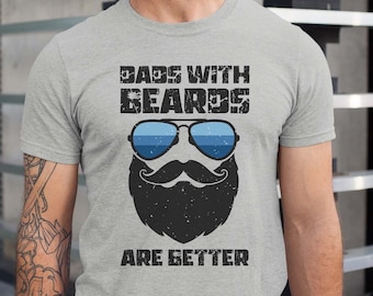 Puede incluir: Una camiseta gris con el texto "Dads with Beards Are Better" y una ilustración de dibujos animados de un hombre barbudo con gafas de sol.