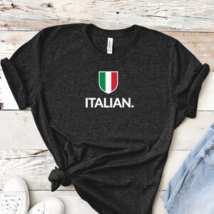 May include: A dark grey t-shirt with a white Italian flag graphic and the text "ITALIAN." printed on the front.