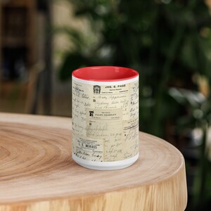 Op de afbeelding: Een witte keramische mok met een rode rand heeft een vintage ontwerp van handgeschreven recepten en apotheeklabels. De mok is bedrukt met de tekst "JAS. E. PAGE" en "PAGEN'S PHARMACY".