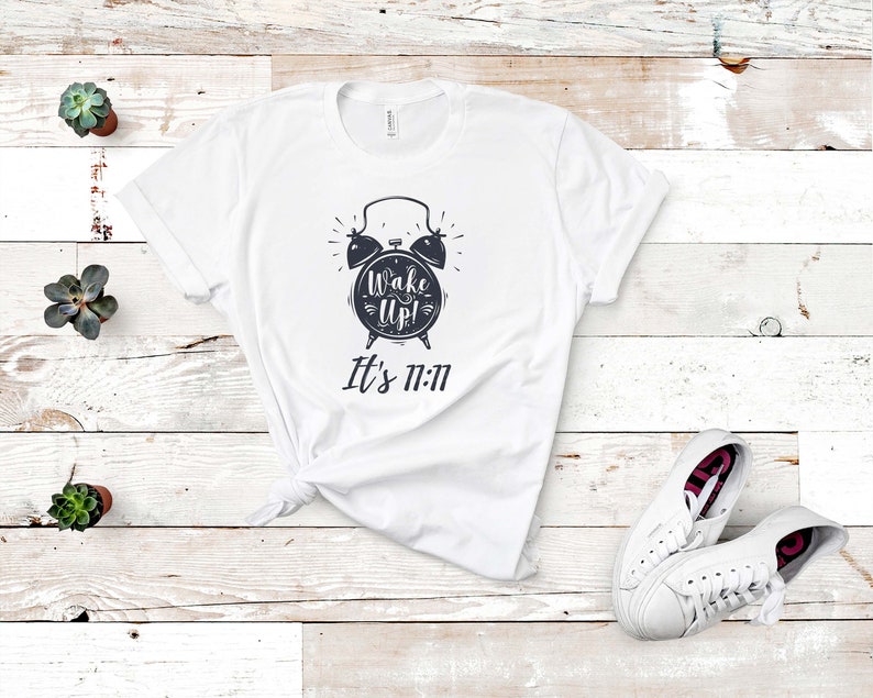 May include: White t-shirt with a black and white alarm clock graphic and the text "Wake Up! It's 11:11"