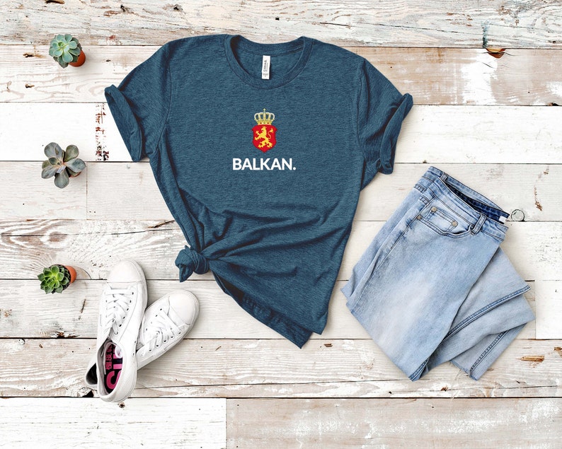 K&ouml;nnte beinhalten: Ein dunkelblaues T-Shirt mit einem wei&szlig;en Aufdruck eines Wappens und dem Wort "BALKAN."