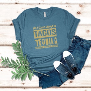 Pode incluir: Uma camiseta azul turquesa com o texto "All I Care About Is Tacos Tequila And Like Maybe 3 People" em uma fonte amarela desbotada.