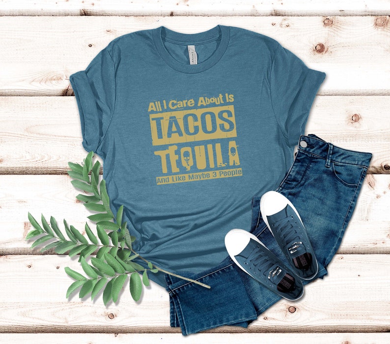 Pode incluir: Uma camiseta azul turquesa com o texto "All I Care About Is Tacos Tequila And Like Maybe 3 People" em uma fonte amarela desbotada.