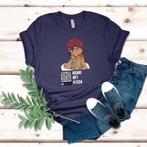 May include: Navy blue t-shirt featuring a graphic of a woman with red hair and a QR code. The text on the shirt reads "KISAKI NFT #1234" and "SCAN ME". The shirt is paired with blue jeans and white-soled sneakers.