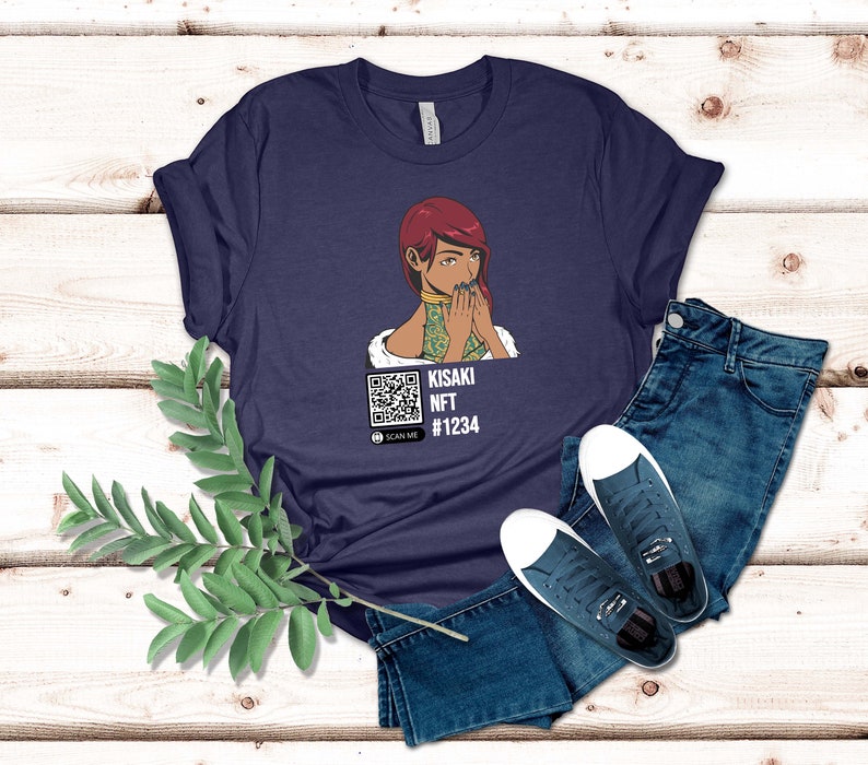 May include: Navy blue t-shirt featuring a graphic of a woman with red hair and a QR code. The text on the shirt reads "KISAKI NFT #1234" and "SCAN ME". The shirt is paired with blue jeans and white-soled sneakers.
