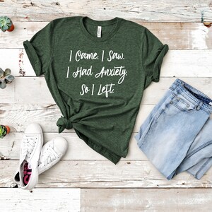 May include: A green t-shirt with white text that reads "I Came. I Saw. I Had Anxiety. So I Left."