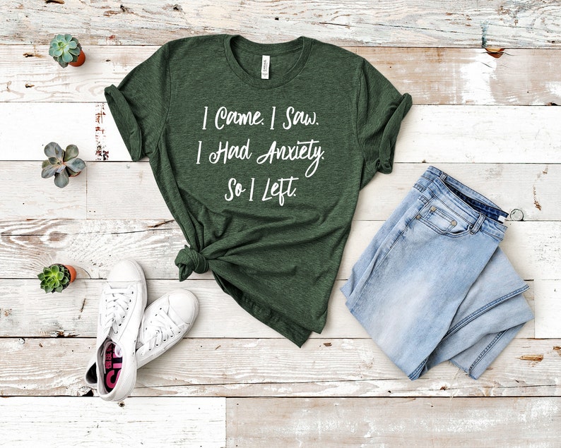 May include: A green t-shirt with white text that reads "I Came. I Saw. I Had Anxiety. So I Left."