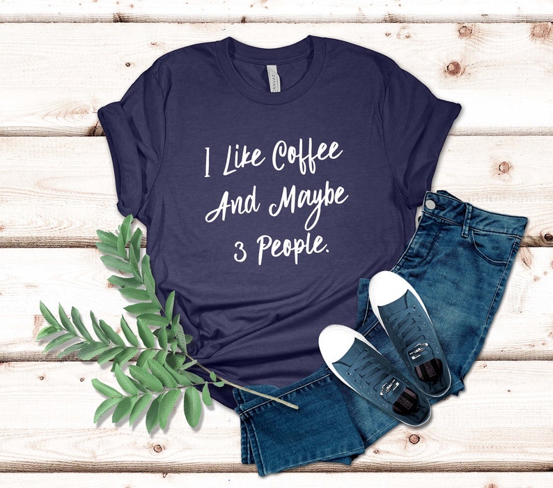 May include: A navy blue t-shirt with white text that reads "I like coffee and maybe 3 people."