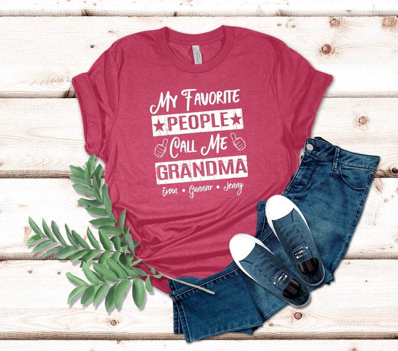 May include: Red t-shirt with the text "My Favorite People Call Me Grandma" and the names "Evan, Gunner, Jenny" printed on it.