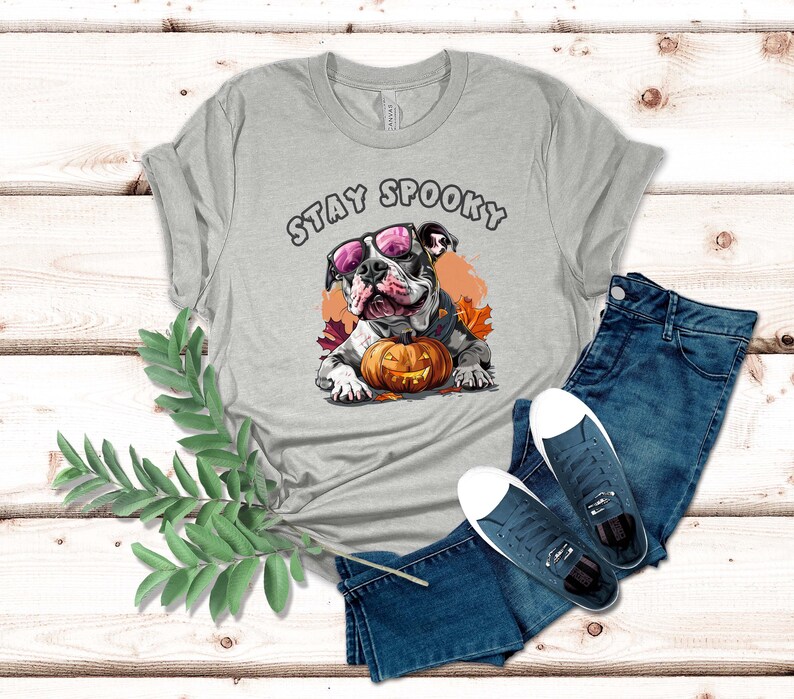 May include: Gray t-shirt with a graphic of a bulldog wearing sunglasses and holding a pumpkin. The text "Stay Spooky" is printed on the shirt.
