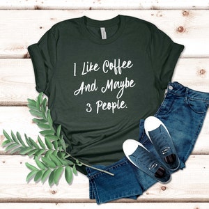 May include: A dark green t-shirt with the text "I like coffee and maybe 3 people." printed in white.