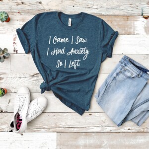 May include: A teal blue t-shirt with the text "I came. I saw. I had anxiety. So I left." printed in white.