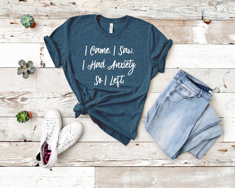 May include: A teal blue t-shirt with the text "I came. I saw. I had anxiety. So I left." printed in white.