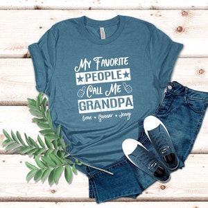 May include: A teal blue t-shirt with the text "My Favorite People Call Me Grandpa" in white. The names "Evan, Gunnar, Jenny" are listed below the text.