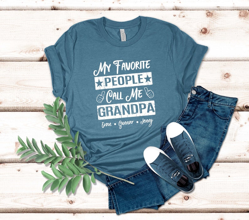 May include: A teal blue t-shirt with the text "My Favorite People Call Me Grandpa" in white. The names "Evan, Gunnar, Jenny" are listed below the text.
