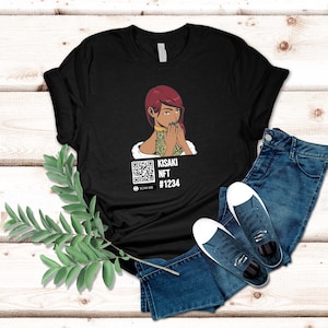 May include: Black t-shirt featuring a graphic of a woman with red hair and a QR code. The text "KISAKI NFT #1234" is below the graphic. The shirt is paired with blue jeans and white sneakers.