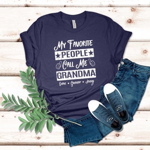 May include: Navy blue t-shirt with white text that reads "My Favorite People Call Me Grandma" with three names listed below: Evan, Gunnar, Jenny.